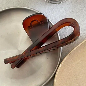 Détail d'une pince à cheveux ambre avec design géométrique en U sur plateau métallique