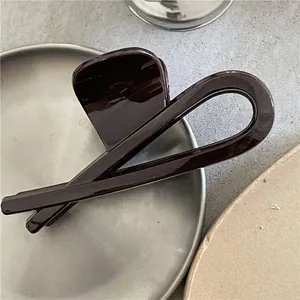 Gros plan sur une grande pince à cheveux marron chocolat au design géométrique brillant