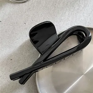 Détail d'une grande pince à cheveux noire brillante au design géométrique minimaliste