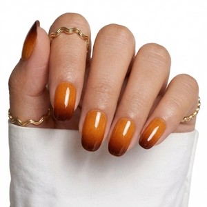 Close-up of amber gradient press-on nails with high-gloss finish and golden ring