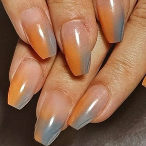 Detail of long coffin press-on nails featuring orange and blue gradient glossy finish