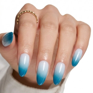 Close-up of glossy ice-blue gradient almond press-on nails with a minimalist look