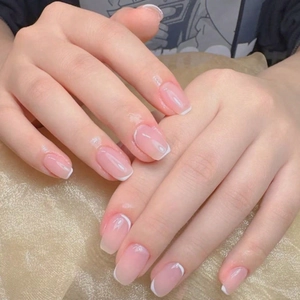 Close-up of minimalist French press-on nails with nude pink base and thin white tips
