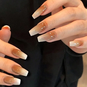 Detailed view of long coffin-shaped press-on nails with brown to cream ombre finish