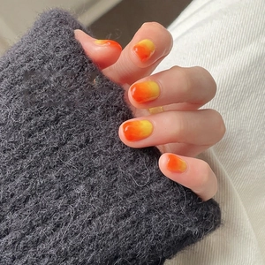 Detail showing sunset orange gradient nails with a polished round shape finish
