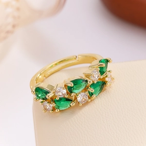 Macro view of adjustable gold ring featuring pear-cut green and round clear crystals