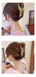 Detail of a large strawberry hair claw clip with pearls on brown hair in a cozy setting