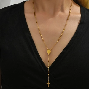 Polished gold stainless steel choker with rosary beads and cross pendant on a model