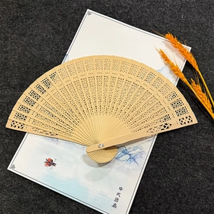 Detailed view of hollow carved wooden fan with intricate floral patterns and smooth finish