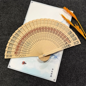 Macro detail of 8-inch sandalwood folding fan featuring hollow dolphin and flower patterns