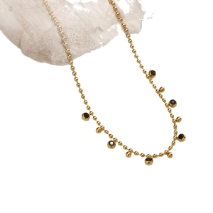 Gold beaded necklace with black gemstone charms and golden spherical fringe accents