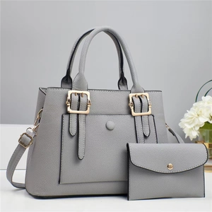 Detail of grey pebbled leather tote bag with matching envelope pouch and gold buckles