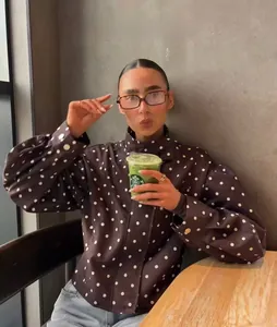 Woman wearing a brown polka dot stand collar jacket in a cozy cafe setting