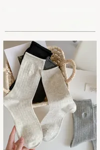 Détail de chaussettes grises avec broderie coeur dans un panier en osier
