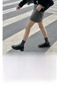 Gros plan de chaussettes grises brodées de cœurs portées avec des mocassins noirs en ville