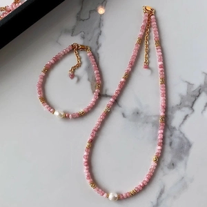 Detailed close-up of beaded necklace and bracelet with pink stones and white pearls