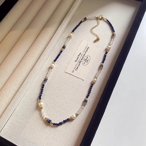 Macro shot of freshwater pearl and blue gemstone beaded necklace with golden lobster clasp