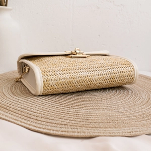 Natural straw woven crossbody bag with cream leather trim and gold twist lock closure