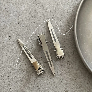 Detailed macro view of silver metallic duckbill hair clips on a grey stone texture surface
