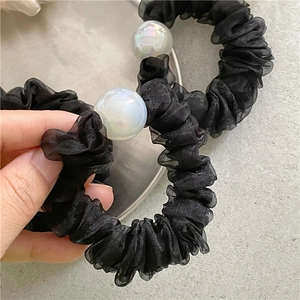 Detailed macro shot of black organza scrunchies with iridescent pearl accents