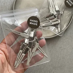 Set of 10 silver metal duckbill hair clips in handmade packaging for styling