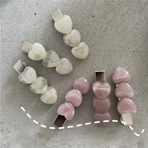 Detail of marble pattern resin heart hair clips in cream white and dusty pink colors