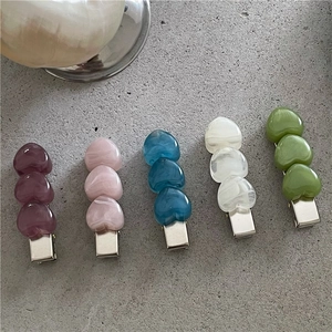 Elegant marble texture heart-shaped hair clips in various pastel colors on a stone surface