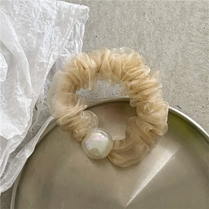 Detailed close-up of champagne organza scrunchie with elegant iridescent faux pearl bead