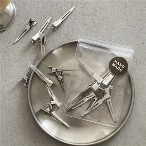 Silver metal hair clips in packaging with handmade sticker on a sleek metal tray