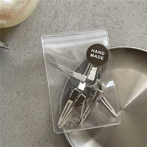 Detailed view of silver metal hair clips in clear packaging with a round handmade label