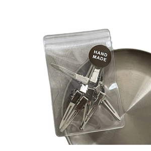 Set of silver metal duckbill hair clips in transparent packaging on stainless steel tray