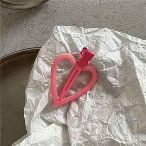 Détail d'une pince à cheveux en acrylique rose en forme de cœur avec pince assortie