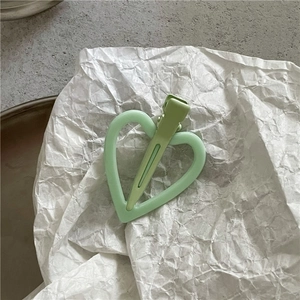 Vue détaillée d'une pince à cheveux en forme de cœur vert clair avec une finition mate