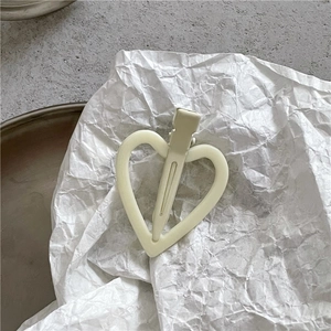 Gros plan d'une pince à cheveux en forme de cœur crème mat sur papier blanc