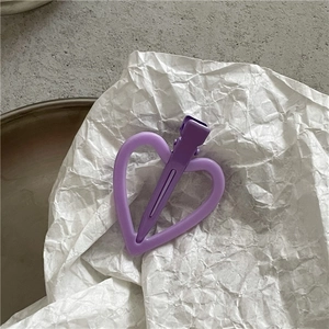 Gros plan d'une pince à cheveux mate en forme de cœur lavande sur un papier texturé