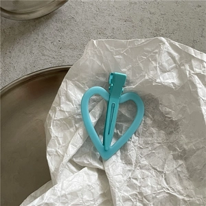 Gros plan d'une pince à cheveux cœur bleu clair sur fond de papier blanc texturé