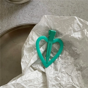 Détail d'une pince à cheveux mate vert menthe en forme de cœur avec design bec de canard