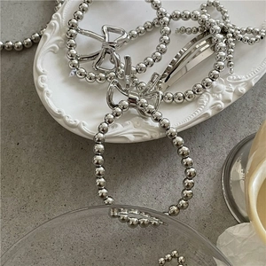 Detail shot of S925 sterling silver stamp on metal bow charm with polished beads