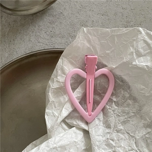 Détail d'une pince à cheveux rose en forme de cœur avec finition mate sur papier blanc