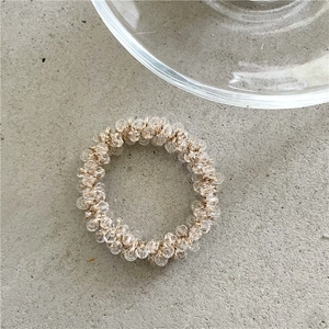 Dettaglio macro dell'elastico per capelli in cristallo con perle sfaccettate champagne