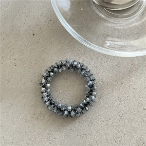 Vista dettagliata delle perle di cristallo grigio fumo sfaccettate su un elastico per capelli