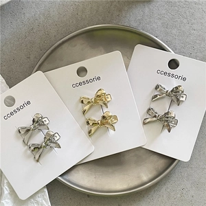 Barrettes à cheveux nœud en métal or et argent sur cartes présentées sur un plateau
