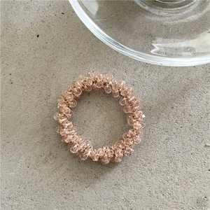 Dettaglio ravvicinato di perline di cristallo rosa sfaccettate su un elastico per capelli