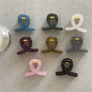 Flat lay of eight colorful resin hair claws in various shades with metallic springs