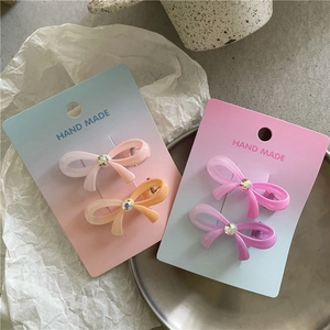 Détail de pinces à cheveux à dégradé avec des strass colorés sur support en carton