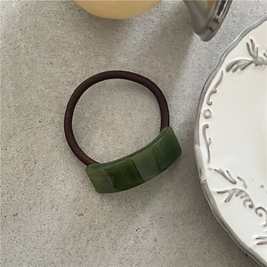 Detail of green resin hair tie with France Handmade text on marble background