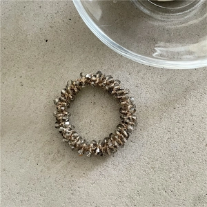 Dettaglio dell'elastico per capelli con perle di cristallo grigio e trama intrecciata