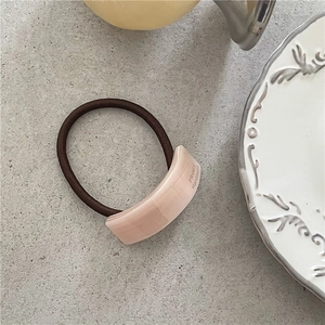 Close-up of pink acetate hair tie with France Handmade text and brown elastic cord