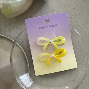 Détails de deux pinces à cheveux nœud dégradé jaune avec strass coloré sur carte