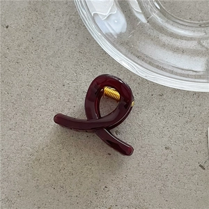 Detail shot of a burgundy translucent resin hair claw with a gold metal spring